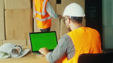 Bir Mühendis Sitedeki Proje İzleme ve Koordinasyon için Yeşil Ekran Bilgisayarı Kullanıyor. Bu Resim Modern İnşaatta Proje Yönetiminin Akıtılmasında Dijital Araçların Rolünü Vurgular.