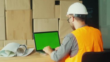 Bir Mühendis Sitedeki Proje İzleme ve Koordinasyon için Yeşil Ekran Bilgisayarı Kullanıyor. Bu Resim Modern İnşaatta Proje Yönetiminin Akıtılmasında Dijital Araçların Rolünü Vurgular.