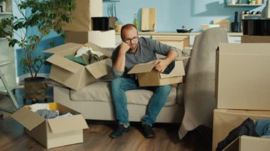 Bir Kişi Ait Olduğu Gibi Paketler, Anılar Arasında Sıralanır, ve Eski Evlerine Veda Eder, Hayattaki Yeni Bir Bölüm İçin Hazırlanıyor. İlerlemenin Duygusal Geçişi ve Heyecanını Vurguluyor.