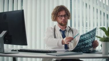 Modern bir ofiste çalışan bir doktor, bilgisayarındaki dijital tıbbi verileri ve röntgenleri doğru tanı koyabilmek için analiz ediyor. Sağlık, Hassasiyet ve Modern Teşhis Tekniklerinde Dijital Veri.