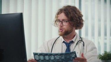 Modern bir ofiste çalışan bir doktor, bilgisayarındaki dijital tıbbi verileri ve röntgenleri doğru tanı koyabilmek için analiz ediyor. Sağlık, Hassasiyet ve Modern Teşhis Tekniklerinde Dijital Veri.