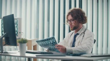 Modern bir ofiste çalışan bir doktor, bilgisayarındaki dijital tıbbi verileri ve röntgenleri doğru tanı koyabilmek için analiz ediyor. Sağlık, Hassasiyet ve Modern Teşhis Tekniklerinde Dijital Veri.