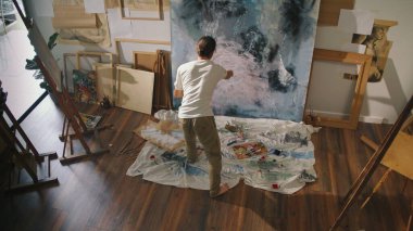 A Young Artist Paints on the Floor in His Studio, Surrounded by His Work. Art Serves as a Means of Self-Expression and Stress Relief, Helping Him Overcome Internal Conflicts and Find Emotional Balance clipart