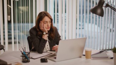 Yorgun bir iş kadını ofiste geç saatlere kadar oturur, bilgisayarında çalışmak için esneme ve mücadele eder. İşyeri Yorgunluğu, Uzun Saatler ve Üretken Kalmaya Çalışırken Yorgunluk kavramı