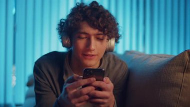 Dijital Detox, Akıl Sağlığı, Odaklanma Modu. Man, Kanepe Kaydırma Telefonunda Rahatlıyor, Muhtemelen Podcast veya Browsing dinliyor. Dijital Çağ 'da Günlük Kişisel Bakım ve Yavaş Yaşam