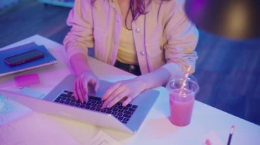 Yaratıcı Akış, Z Geni Çalışma Tarzı, Tasarım Düşüncesi. Kadın, Neon Home Office 'de Laptop' ta çalışıyor, Harekete Geçen Ellerin Kapanışı. Resmi Olmayan Çalışma Alanında Odaklanmış Dijital Süreç ve Estetik İfade