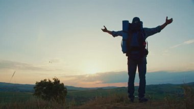 Ruhani Neşe, Doğaya İnanç, Minnettar Yaşam. Sırt çantalı son sınıf öğrencisi, Sunset 'te bir dağın zirvesinde kollarını kaldırarak duruyor, Tanrı' yı güçlü bir ibadet anında ve doğada dehşet içinde överek övüyor.
