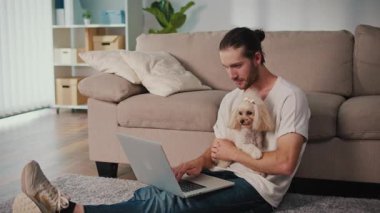 Duygusal Destek, Akıl Sağlığı, İş-Yaşam Dengesi. Evden Genç Adam Çalışıyor, Köpeği Yanında Otururken Çevrimiçi Toplantıya Odaklanıyor. Dijital Bağlantının Sakin Anı ve Hayvan güdümlü İstikrar