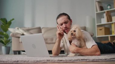 İş-Hayat Bütünleşmesi, Odaklanmış Rutin. Dikey video. Genç adam, köpeğiyle birlikte evde dizüstü bilgisayarda çalışıyor. Sakin Duygusal İstikrar, Rahatlık ve Her Gün Hayvanlara Özel Verimlilik Sahnesi