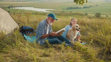 Aile Bağları Açık havada. Son sınıf öğrencisi kızı, neşe içinde köpeğiyle oynayan genç bir kadın çadırın yanında kitap okuyor. Barışçıl, Doğanın, Aile ve Arkadaşlığın Bağlı Anı
