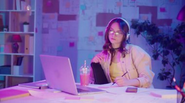 Dikkatli Yaratıcılık, Duygusal Odaklanma, Gen Z Tarzı. Kulaklıklı Kadın, Gece Müzik Dinlerken Neon Room 'da Çizim Yapıyor. Kişisel İlham Anı, Sakin ve Etkileyici Akış