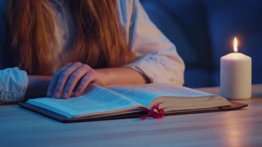 Genç Kadın Elleri 'nin yakın çekimi Kutsal İncil' in nazikçe çevirdiği sayfalar, Soft Candlelight 'tan Kutsal Kitap okuyor. Sakin ve Huzurlu Atmosfer, Akşam İncil Çalışması, İnanç ve Ruhani Yansıma.