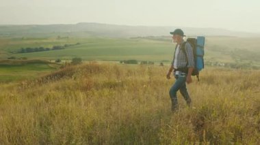 Amaçlı Yolculuk, Geç Yaşam Keşfi. Yaşlı adam panoramik dağ manzarasında yürüyor, Ağaçlar, Çimenler ve Gökyüzü ile çevrili. Sonraki yıllarda Doğa ve Kişisel Büyümeyi Kucaklayan Ruhsal Macera