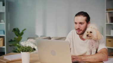 Mikro neşeler, Akıl Sağlığı, Günlük Denge. Genç Adam, köpeği ile koltukta iletişim kurarken dizüstü bilgisayarda çalışıyor. Yumuşak, destekleyici bir an Harmanlayıcı Odak, Duygu ve Bağlantı