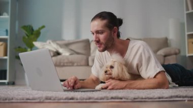 İş-Hayat Bütünleşmesi, Odaklanmış Rutin. Dikey video. Genç adam, köpeğiyle birlikte evde dizüstü bilgisayarda çalışıyor. Sakin Duygusal İstikrar, Rahatlık ve Her Gün Hayvanlara Özel Verimlilik Sahnesi