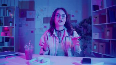 Sosyal medya, içerik yaratma, görsel kimlik. Kadın Neon Home Studio 'da oturuyor ve Vlog' unu kaydediyor. Genel Z Çevrimiçi İletişim için Parlak Kişisel Alan ve Dijital Varlık