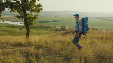 Amaçlı Yolculuk, Geç Yaşam Keşfi. Yaşlı adam panoramik dağ manzarasında yürüyor, Ağaçlar, Çimenler ve Gökyüzü ile çevrili. Sonraki yıllarda Doğa ve Kişisel Büyümeyi Kucaklayan Ruhsal Macera