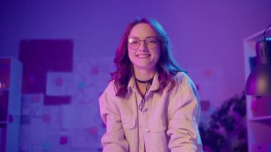 Modern Profesyonellik, Dijital Kimlik, Gelecekteki Odaklanma. Kendine güvenen genç kadın Neon Room 'daki kameraya bakıyor. Moda, netlik ve kişilikle öncülük etmeye hazır yeni nesil bir profesyonelin portresi