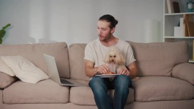 Basit Mutluluklar, Samimi Anlar, Günlük Bond. Genç adam köpeği ile koltukta oturur, gevşemiş zamanı paylaşır ve patates kızartması yer. Dürüst, Sıcak Dostluk Sahnesi, Yemek ve Evde Rahatlık
