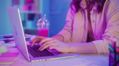 Yaratıcı Akış, Z Geni Çalışma Tarzı, Tasarım Düşüncesi. Kadın, Neon Home Office 'de Laptop' ta çalışıyor, Harekete Geçen Ellerin Kapanışı. Resmi Olmayan Çalışma Alanında Odaklanmış Dijital Süreç ve Estetik İfade