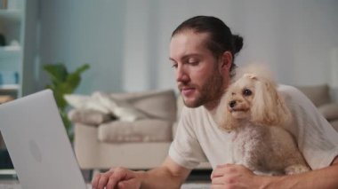 İş-Hayat Bütünleşmesi, Odaklanmış Rutin. Dikey video. Genç adam, köpeğiyle birlikte evde dizüstü bilgisayarda çalışıyor. Sakin Duygusal İstikrar, Rahatlık ve Her Gün Hayvanlara Özel Verimlilik Sahnesi