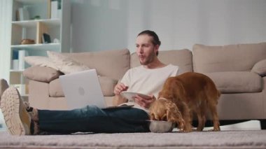 Sağlıklı rutin, Evcil Hayvan Besleme, Dijital Denge. Köpeği yakınlarda kendi yemeğinin tadını çıkarırken adam masa başında çalışıyor ve yiyor. Sakin, Senkronize Sağlık ve Günlük Odaklanma