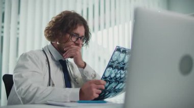 Bilgisayar ekranındaki röntgenleri ve CT taramalarını analiz eden bir doktor, Dijital Tıbbi Verileri doğru tanı ve tedavi planları sağlamak için gözden geçirir. Tıbbi Profesyonellik ve Uzman Bakımı kavramı