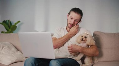 Duygusal Destek, Akıl Sağlığı, İş-Yaşam Dengesi. Evden Genç Adam Çalışıyor, Köpeği Yanında Otururken Çevrimiçi Toplantıya Odaklanıyor. Dijital Bağlantının Sakin Anı ve Hayvan güdümlü İstikrar