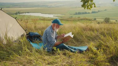 Sessiz Emeklilik, İhtiyatlı Yaşlılık, Hayvan Bağlama. Son sınıf öğrencisi köpeği ile çadırda oturur ve doğada kitap okur. Huzurlu Yansıma, Arkadaşlık ve Yavaş Açık Hava Yaşamı Anı