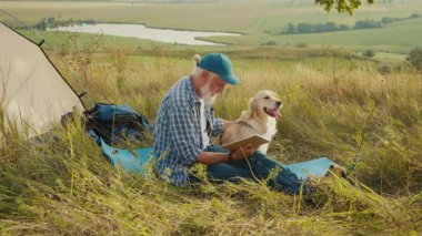 Sessiz Emeklilik, İhtiyatlı Yaşlılık, Hayvan Bağlama. Son sınıf öğrencisi köpeği ile çadırda oturur ve doğada kitap okur. Huzurlu Yansıma, Arkadaşlık ve Yavaş Açık Hava Yaşamı Anı