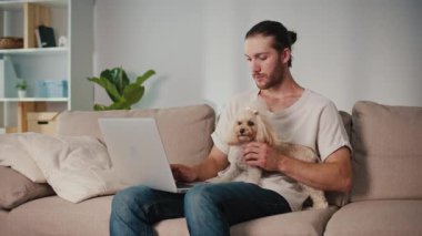 Duygusal Destek, Akıl Sağlığı, İş-Yaşam Dengesi. Evden Genç Adam Çalışıyor, Köpeği Yanında Otururken Çevrimiçi Toplantıya Odaklanıyor. Dijital Bağlantının Sakin Anı ve Hayvan güdümlü İstikrar