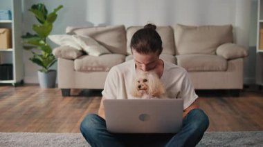 İş-Hayat Bütünleşmesi, Odaklanmış Rutin. Dikey video. Genç adam, köpeğiyle birlikte evde dizüstü bilgisayarda çalışıyor. Sakin Duygusal İstikrar, Rahatlık ve Her Gün Hayvanlara Özel Verimlilik Sahnesi