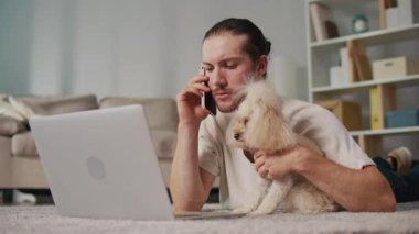 İş-Hayat Bütünleşmesi, Odaklanmış Rutin. Dikey video. Genç adam, köpeğiyle birlikte evde dizüstü bilgisayarda çalışıyor. Sakin Duygusal İstikrar, Rahatlık ve Her Gün Hayvanlara Özel Verimlilik Sahnesi