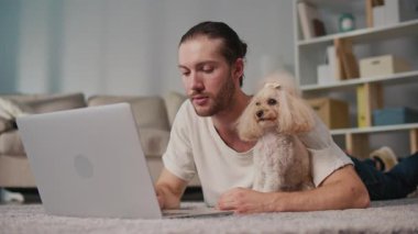 İş-Hayat Bütünleşmesi, Odaklanmış Rutin. Dikey video. Genç adam, köpeğiyle birlikte evde dizüstü bilgisayarda çalışıyor. Sakin Duygusal İstikrar, Rahatlık ve Her Gün Hayvanlara Özel Verimlilik Sahnesi