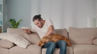 Hayvan Sağlığı, Sağlıklı Paylaşım, Sıcak Bağ. Dikey video. Man ve Dog koltuğa oturur, dinlenir. Köpek, sahibinden patates kızartması aldı. Gerçek Bağlantı, Bakım ve Günlük Denge Anı