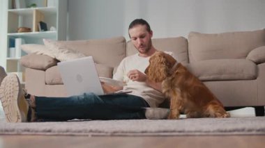 Sağlıklı rutin, Evcil Hayvan Besleme, Dijital Denge. Köpeği yakınlarda kendi yemeğinin tadını çıkarırken adam masa başında çalışıyor ve yiyor. Sakin, Senkronize Sağlık ve Günlük Odaklanma