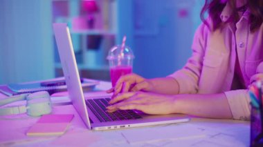 Yaratıcı Akış, Z Geni Çalışma Tarzı, Tasarım Düşüncesi. Kadın, Neon Home Office 'de Laptop' ta çalışıyor, Harekete Geçen Ellerin Kapanışı. Resmi Olmayan Çalışma Alanında Odaklanmış Dijital Süreç ve Estetik İfade