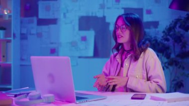 Dijital özgüven, uzaktan çalışma, neon ruh hali. Kadın şık bir İçişleri Bakanlığı 'nda oturuyor ve bir iş videosunda konuşuyor. Kalın Yaratıcı Alan 'da Odaklanma ve Otoriteyi Temizle