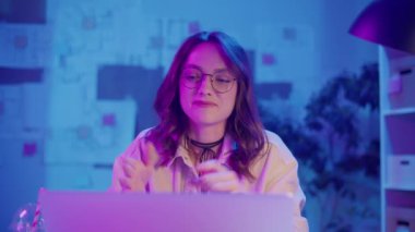 Sanal Liderlik, Uzaktan Çalışma, Neon Estetik. Yaratıcı Neon Ofisindeki Kadın Bir İş Videosu Görüşmesi Yönetti. Gayri resmi ama Profesyonel Çevrede Güvenilir Dijital Varlık