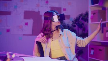 Karışık Gerçeklik, Enmersive Tech, Gen Z Future. Neon-Lit Room 'da oturan kız VR ya da AR gözlükleri takıyor, Dijital Alanla etkileşimde. Görsel olarak Yoğun Sanal Dünya Kişisel Anı