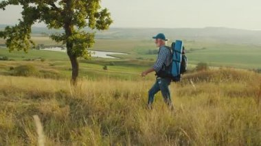 Amaçlı Yolculuk, Geç Yaşam Keşfi. Yaşlı adam panoramik dağ manzarasında yürüyor, Ağaçlar, Çimenler ve Gökyüzü ile çevrili. Sonraki yıllarda Doğa ve Kişisel Büyümeyi Kucaklayan Ruhsal Macera