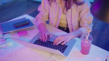 Yaratıcı Akış, Z Geni Çalışma Tarzı, Tasarım Düşüncesi. Kadın, Neon Home Office 'de Laptop' ta çalışıyor, Harekete Geçen Ellerin Kapanışı. Resmi Olmayan Çalışma Alanında Odaklanmış Dijital Süreç ve Estetik İfade