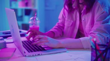Yaratıcı Akış, Z Geni Çalışma Tarzı, Tasarım Düşüncesi. Kadın, Neon Home Office 'de Laptop' ta çalışıyor, Harekete Geçen Ellerin Kapanışı. Resmi Olmayan Çalışma Alanında Odaklanmış Dijital Süreç ve Estetik İfade