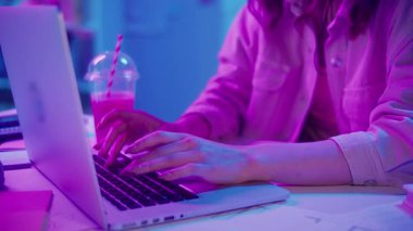 Yaratıcı Akış, Z Geni Çalışma Tarzı, Tasarım Düşüncesi. Kadın, Neon Home Office 'de Laptop' ta çalışıyor, Harekete Geçen Ellerin Kapanışı. Resmi Olmayan Çalışma Alanında Odaklanmış Dijital Süreç ve Estetik İfade
