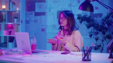 Dijital özgüven, uzaktan çalışma, neon ruh hali. Kadın şık bir İçişleri Bakanlığı 'nda oturuyor ve bir iş videosunda konuşuyor. Kalın Yaratıcı Alan 'da Odaklanma ve Otoriteyi Temizle