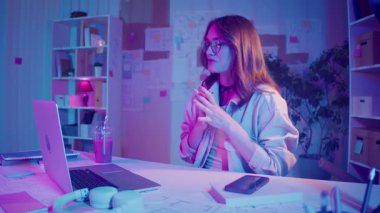 Dijital özgüven, uzaktan çalışma, neon ruh hali. Kadın şık bir İçişleri Bakanlığı 'nda oturuyor ve bir iş videosunda konuşuyor. Kalın Yaratıcı Alan 'da Odaklanma ve Otoriteyi Temizle