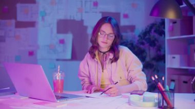 Tasarım Düşünme, Yaratıcı Çalışma Akışı, Görsel Planlama. Laptopun Önündeki Kadın Çizimleri, Duvardaki Taslaklarla çevrili. Kişisel Fikir ve Yapı Stüdyosunda Bir Konsantrasyon Anı