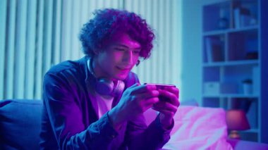 Man, Kanepe Kaydırma Telefonunda Rahatlıyor, Muhtemelen Podcast veya Browsing dinliyor. Günlük Kişisel Bakım ve Dijital Çağ 'da Yavaş Yaşam. Dijital Detox, Akıl Sağlığı, Odaklanma Kipi.