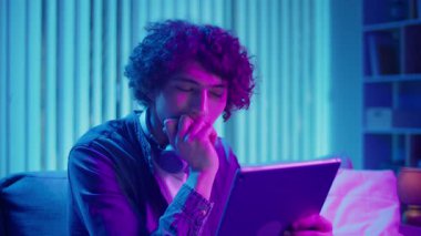 Man, Tablet Kullanarak Koltuğa Rahatlar, Muhtemelen Okuma ve Yayınlama İçeriğini İzler. Günlük Kişisel Bakım ve Dijital Çağ 'da Yavaş Yaşam. Dijital Detox, Akıl Sağlığı, Odaklanma Kipi.