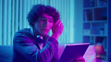 Man, Tablet Kullanarak Koltuğa Rahatlar, Muhtemelen Okuma ve Yayınlama İçeriğini İzler. Günlük Kişisel Bakım ve Dijital Çağ 'da Yavaş Yaşam. Dijital Detox, Akıl Sağlığı, Odaklanma Kipi.